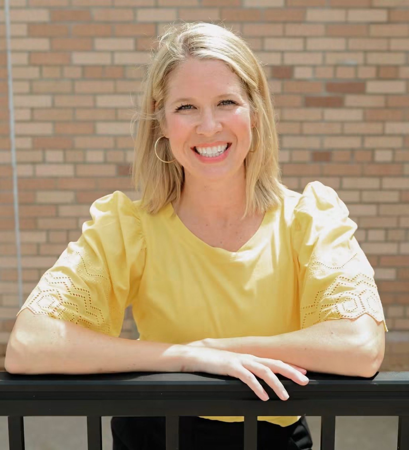 Katie Carstens smiling in a yellow blouse in natural light